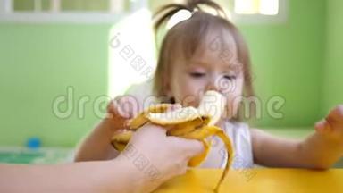 妈妈在<strong>厨房</strong>的桌子旁喂小香蕉。 为<strong>幼儿</strong>补充.. 可爱的零食小子